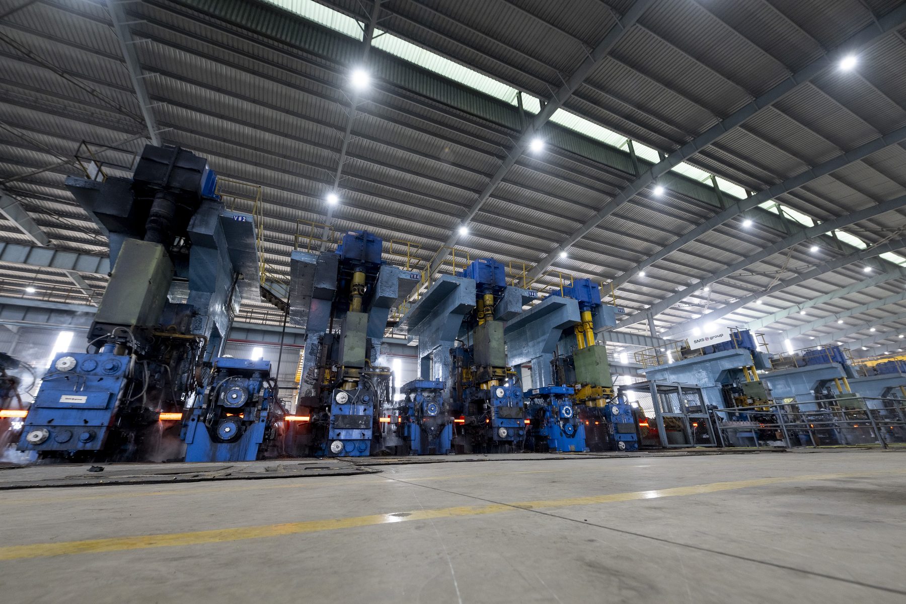 A row of blue rolling stands under the mill roof