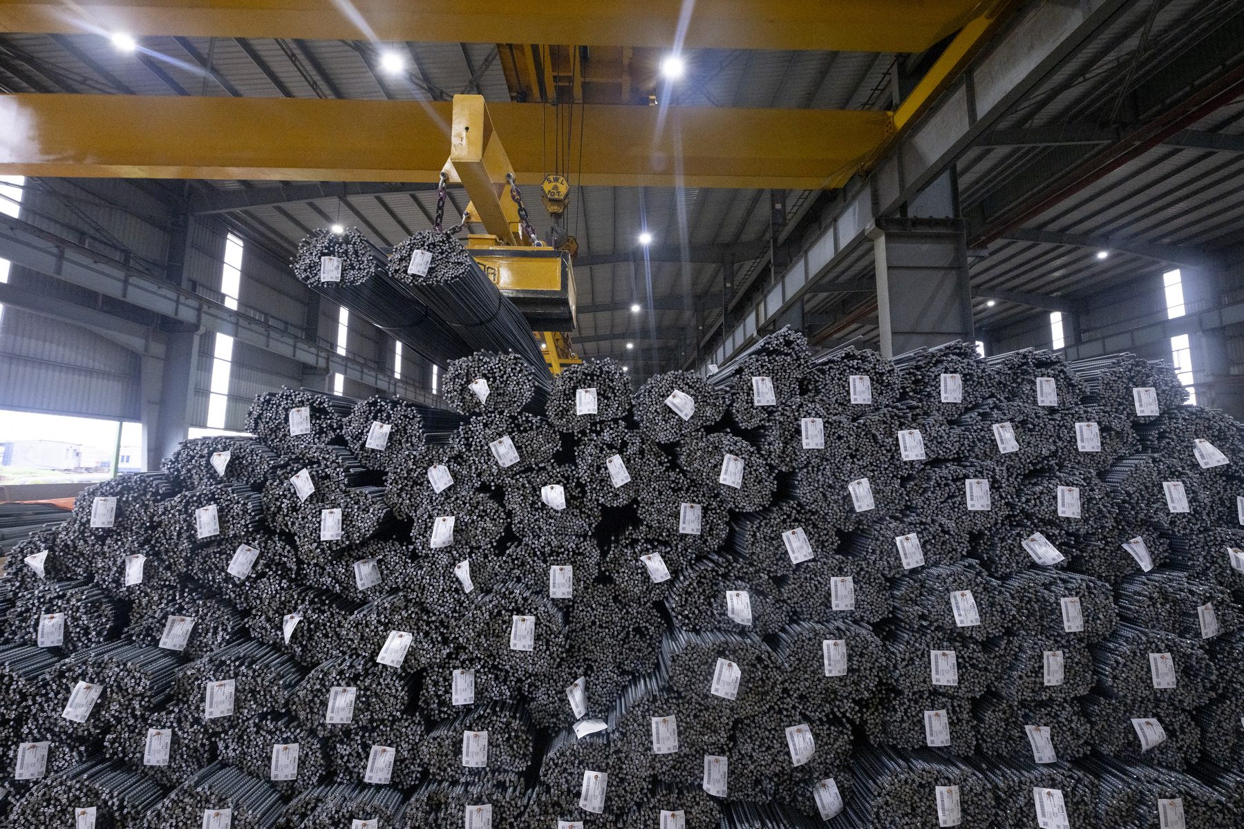 Bundles of rebar stacked in the mill bay, under a crane